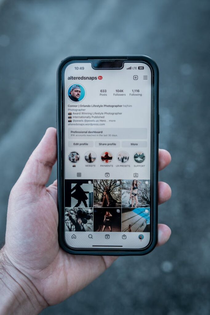 Close-up of a hand holding a smartphone displaying an Instagram profile outdoors.